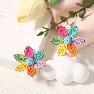 Dettaglio di orecchini a margherita in raffia intrecciata con texture floreali