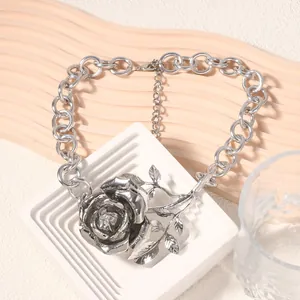 Macro di una collana con pendente a rosa 3D argentata e catena spessa su base minimalista