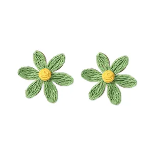 Dettaglio degli orecchini a margherita in rafia fatti a mano con petali verdi e gialli