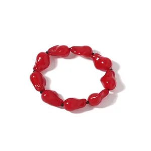 Detailaufnahme eines minimalistischen roten Armbands mit unregelmäßigen Tropfenperlen