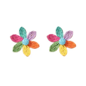 Dettaglio di orecchini a margherita in rafia intrecciata con petali multicolori