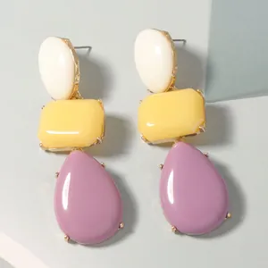 Detail of colorful resin drop earrings with white yellow and purple geometric segments