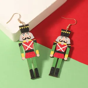 Detalle de pendientes de madera de cascanueces pintados a mano sobre fondo navideño
