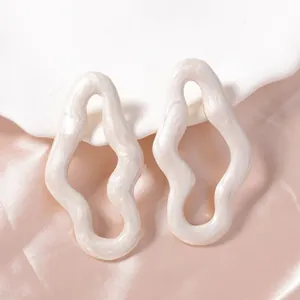Dettaglio degli orecchini a onde irregolari con finitura crema perlata e cangiante