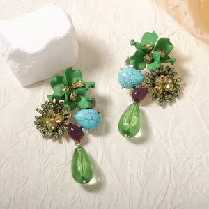 Detailed close-up of retro floral drop earrings with green resin water droplets and stones