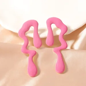 Detalle de los pendientes de esmalte rosa con diseño fluido sobre fondo de seda fina