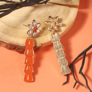 Asymmetric Halloween drop earrings with orange TREAT lettering and gold texture finish