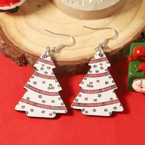 Détail de boucles d'oreilles sapin de Noël en bois avec motifs festifs sur fond rouge
