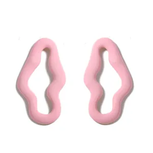 Dettaglio degli orecchini a onde rosa con design traforato minimalista e finitura liscia