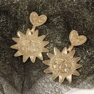 Detailed close-up of golden sunflower heart earrings with retro face relief on black mesh