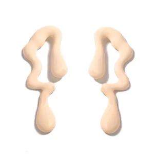 Primer plano de pendientes de gota irregulares color crema con un acabado mate suave