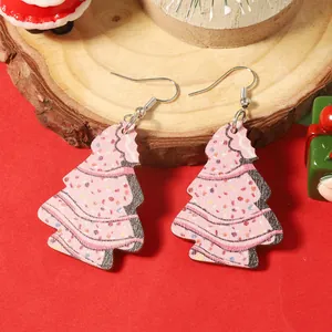 Détail de boucles d'oreilles sapin de Noël en bois rose avec points colorés sur bois