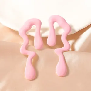Detalle de pendientes rosas en forma de gota con acabado liso sobre seda y cerámica