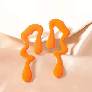 Detalle macro de pendientes de gota naranja vibrante sobre elegante tela de raso