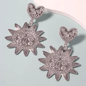 Silver boho heart and sunburst earrings featuring artistic relief face pendants