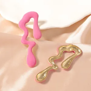 Pendientes abstractos estilo lava en esmalte rosa y metal dorado sobre fondo de satén