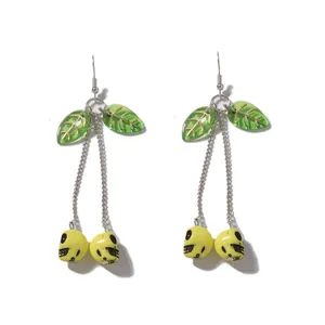 Macro view of cherry-shaped skull long pendants with green resin leaves and yellow beads