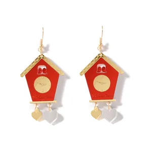 Détail de boucles d'oreilles coucou rouge avec pendentifs cœurs dorés et texte Valentine