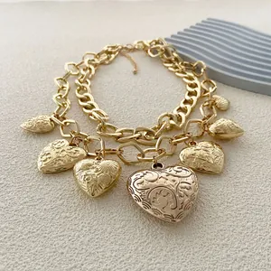 Detalle de collar de doble cadena dorada con colgantes de corazón vintage grabados en relieve