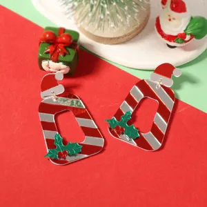 Gros plan de boucles d'oreilles de Noël en acrylique avec rayures rouges et bonnet