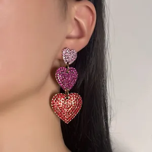 Boucles d'oreilles cœur à trois niveaux avec strass roses et rouges sur un modèle