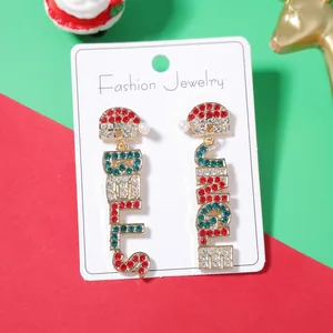 Detalle de pendientes navideños con letras Believe y Jingle con pedrería fina