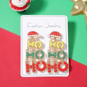 Dettaglio di orecchini natalizi 'HO HO HO' con perline colorate e cappello di Babbo Natale
