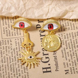 Detailed shot of vintage asymmetric gold earrings featuring evil eye and coin medallion