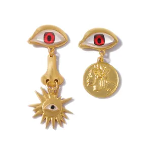 Vintage gold asymmetrical earrings featuring surrealist devil eye and portrait coin charms