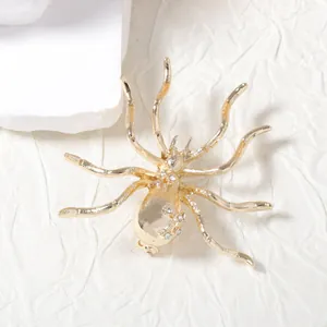 Gold spider brooch with sparkling white crystals on minimalist geometric backdrop