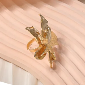 Artistic gold orchid flower adjustable ring with textured metal petals on pink background
