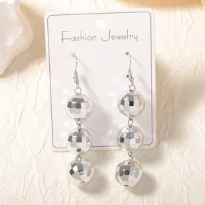 Boucles d'oreilles boules disco argentées avec trois perles géométriques sur carte