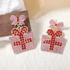 Vista macro de los pendientes de caja de regalo de Navidad con strass rosa y lazo dorado