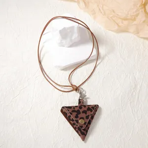 Detail shot of leopard print triangle neck pouch with vintage gold metal clasp closure