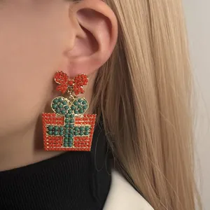 Pendientes de caja de regalo de Navidad con cuentas rojas y verdes en una modelo