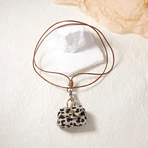 Detail of leopard print mini pouch pendant with bronze snap button and brown lanyard