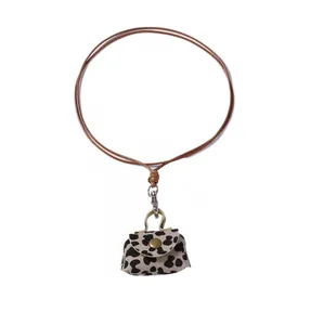 Macro detail of leopard print mini pouch pendant with gold metal clasp and brown cord