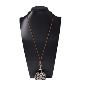 Mini cow print bag pendant necklace with brown cord on a black display stand