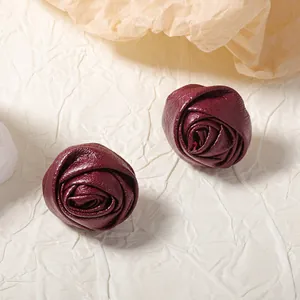 French style wine red leather rose earrings on minimalist textured paper background