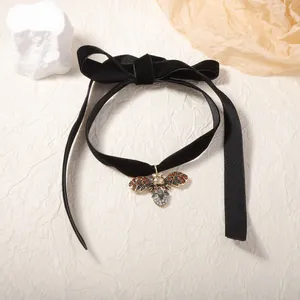 Macro detail of velvet choker featuring a vintage gold bee pendant with rhinestones