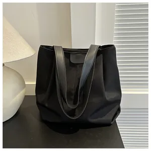 Detalle de bolso tote de lona negra con asas de cuero en un ambiente interior acogedor y cálido