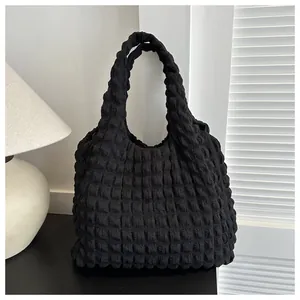 Detail of black pleated popcorn fabric texture on a modern minimalist shoulder bag
