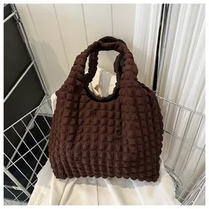 Close-up of deep brown textured fabric handbag with bubble quilted pattern detail