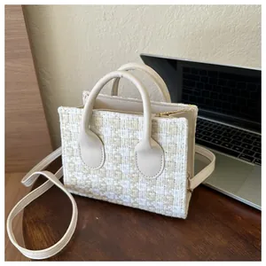 Detail of tweed checkered small tote bag with cream PU handles and gold metal zipper