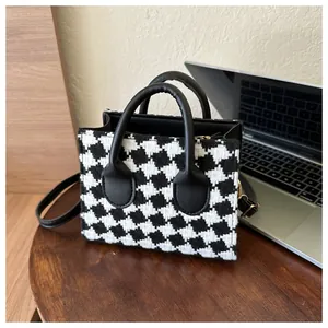 Detail of classic black and white houndstooth tweed mini tote bag on a wooden table