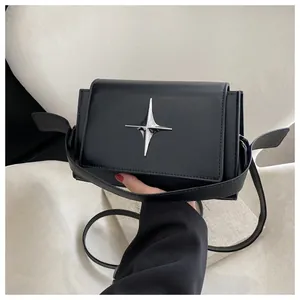 Dettaglio di borsa in pelle nera con un ornamento in metallo a stella a quattro punte