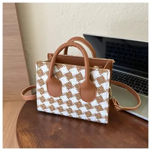 Detail of checkered tweed tote bag with brown faux leather trim and detachable strap