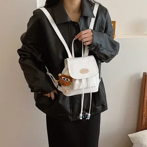 Mini white faux leather backpack with drawstring closure and cute plush charm on model