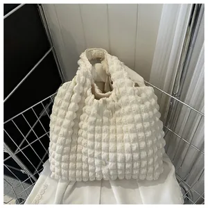 Close-up of the popcorn textured fabric on this off-white pleated shoulder tote bag