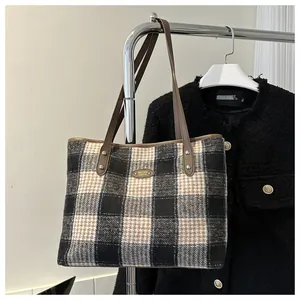 Detailed close-up of checkered tote bag fabric with leather strap and metal logo